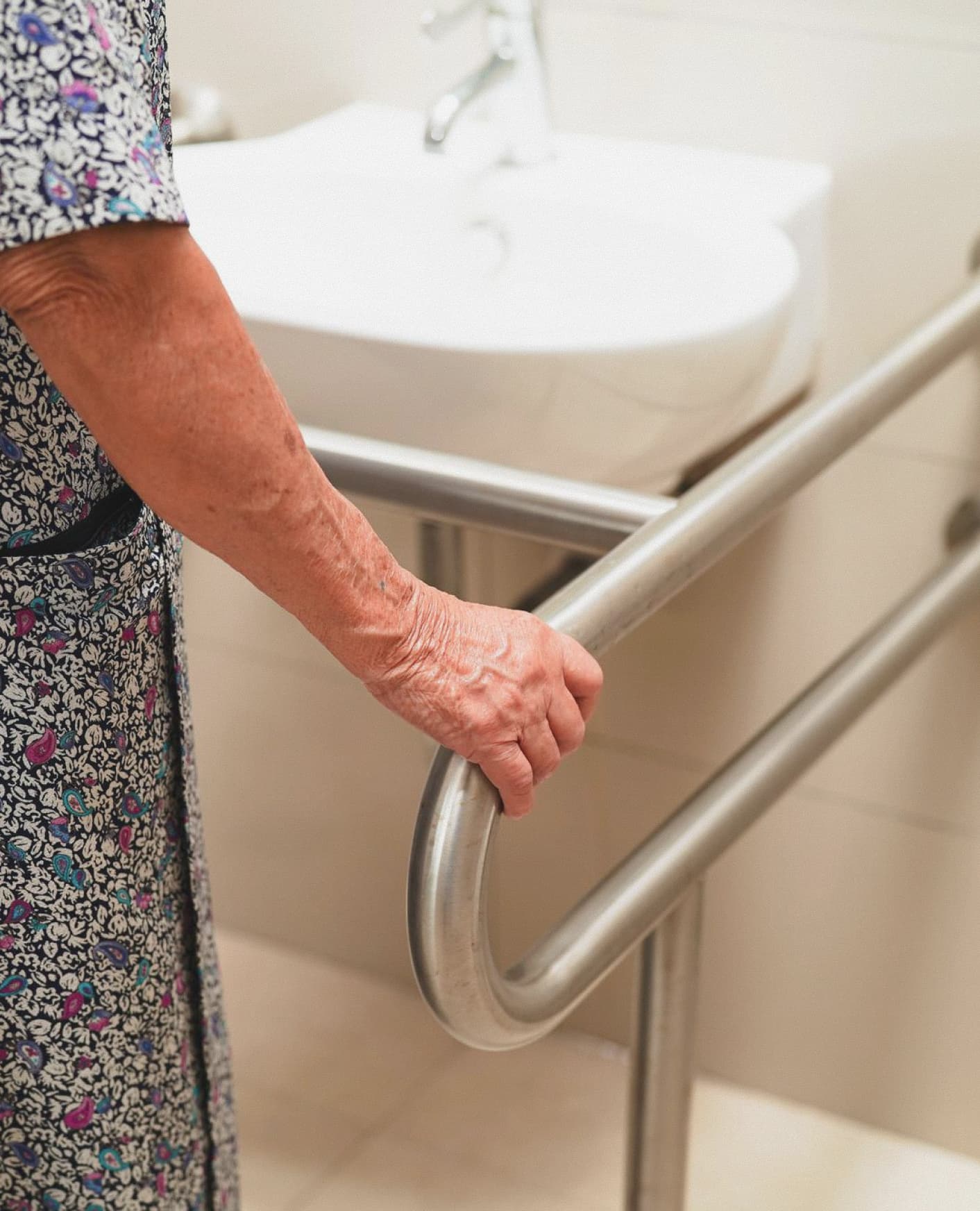Caregiver helping elderly man walk safely upstairs at home