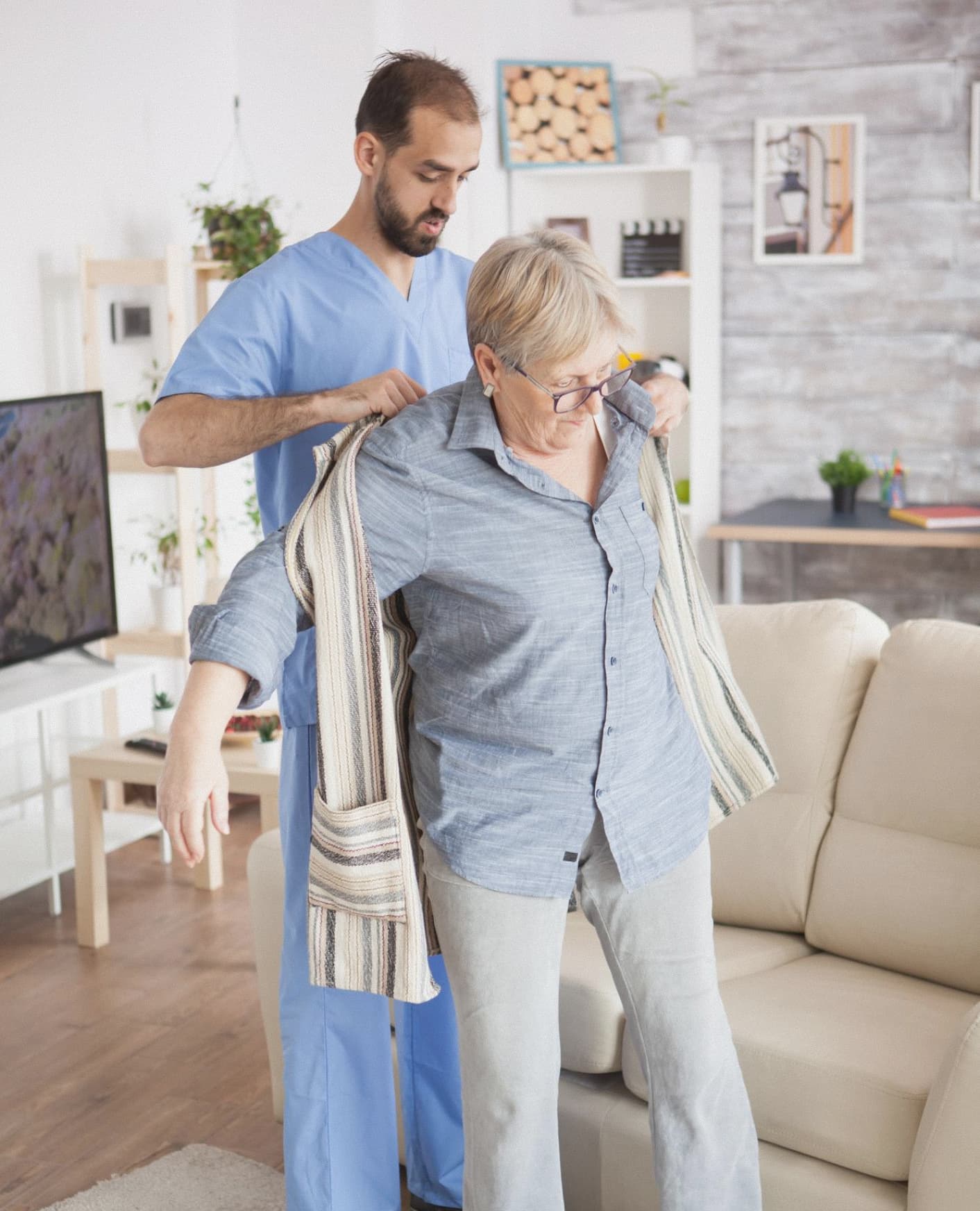 Caregiver helping elderly woman with mobility support at home.