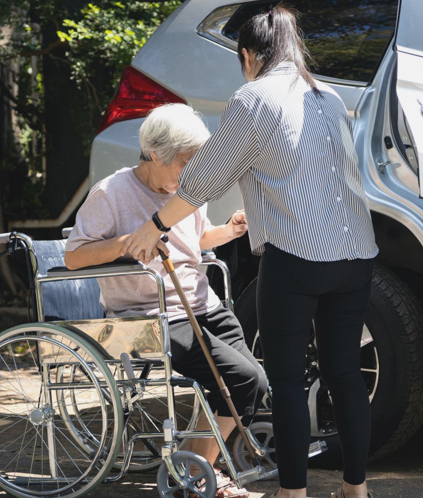 Caregiver pushing senior woman in wheelchair during outdoor activity