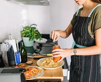 A person in an apron preparing a meal in a home kitchen