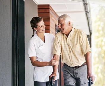 Caregiver walking with elderly man using a walker
