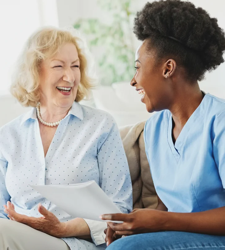 Smiling caregiver talking with elderly woman