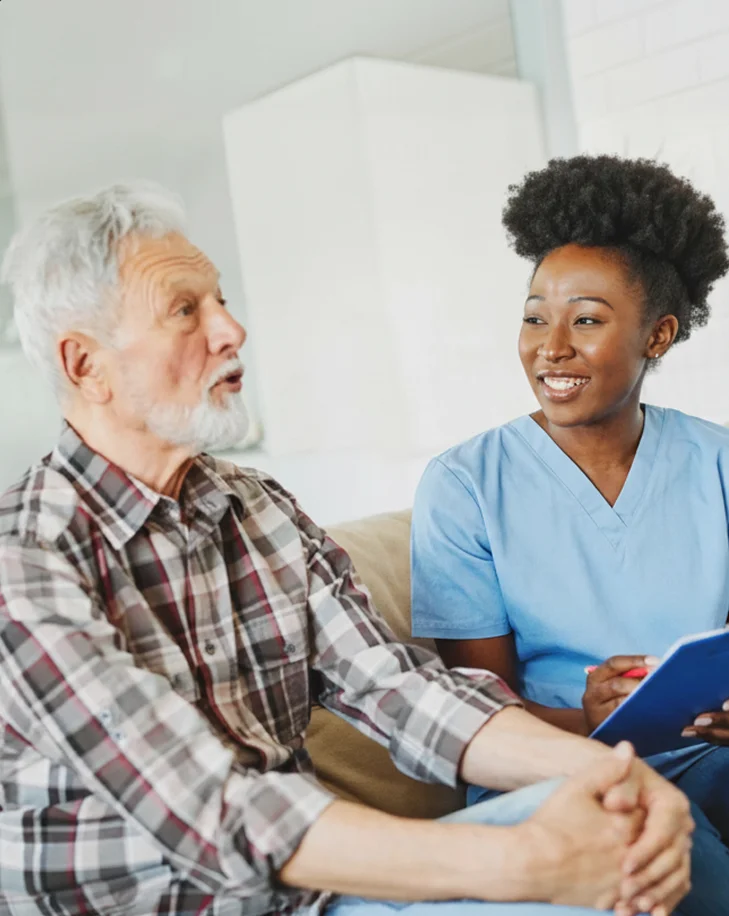 Caregiver talking with elderly man at home