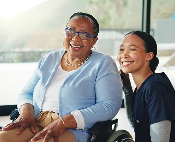Caregiver and senior woman in wheelchair laughing together