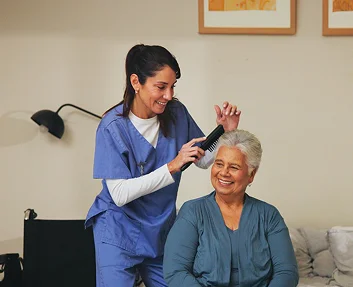 Caregiver brushing smiling senior woman's hair