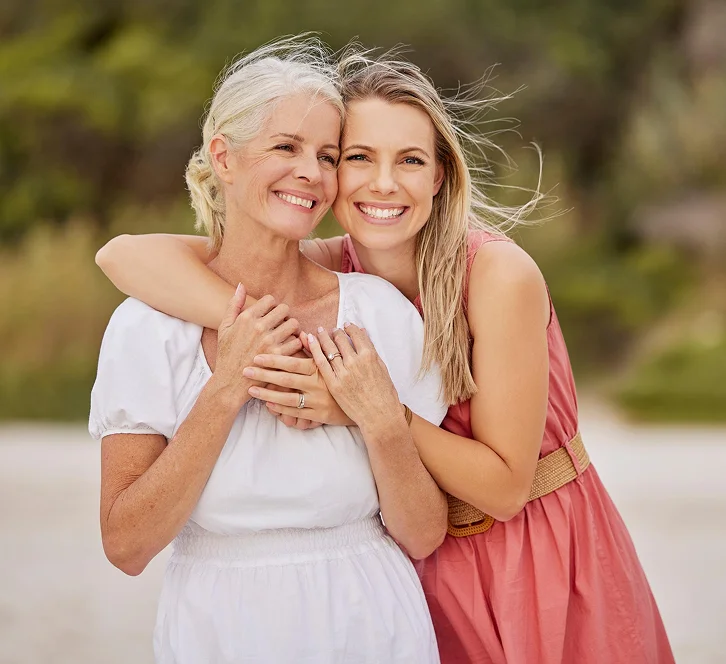 Smiling mother and daughter embracing outdoors