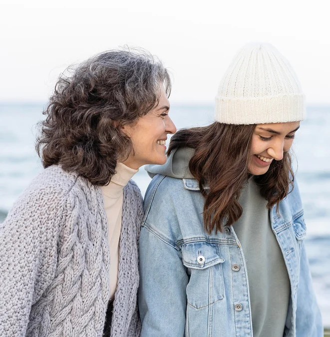 Mother and daughter smiling by the sea