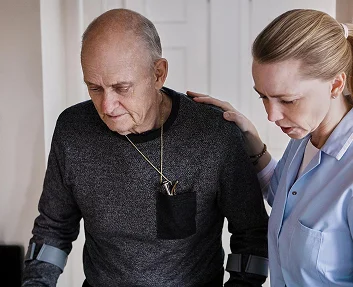 Caregiver supporting elderly man using a walker