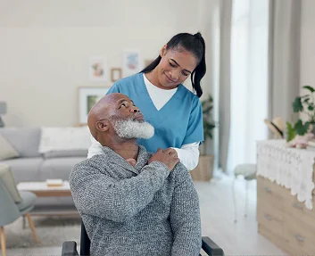 Caregiver smiling at seated elderly man in wheelchair