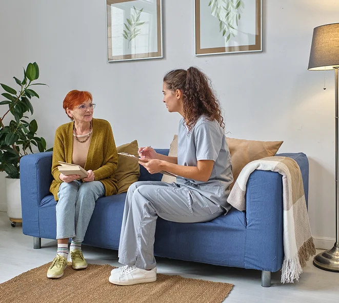 Caregiver talking with senior woman on sofa