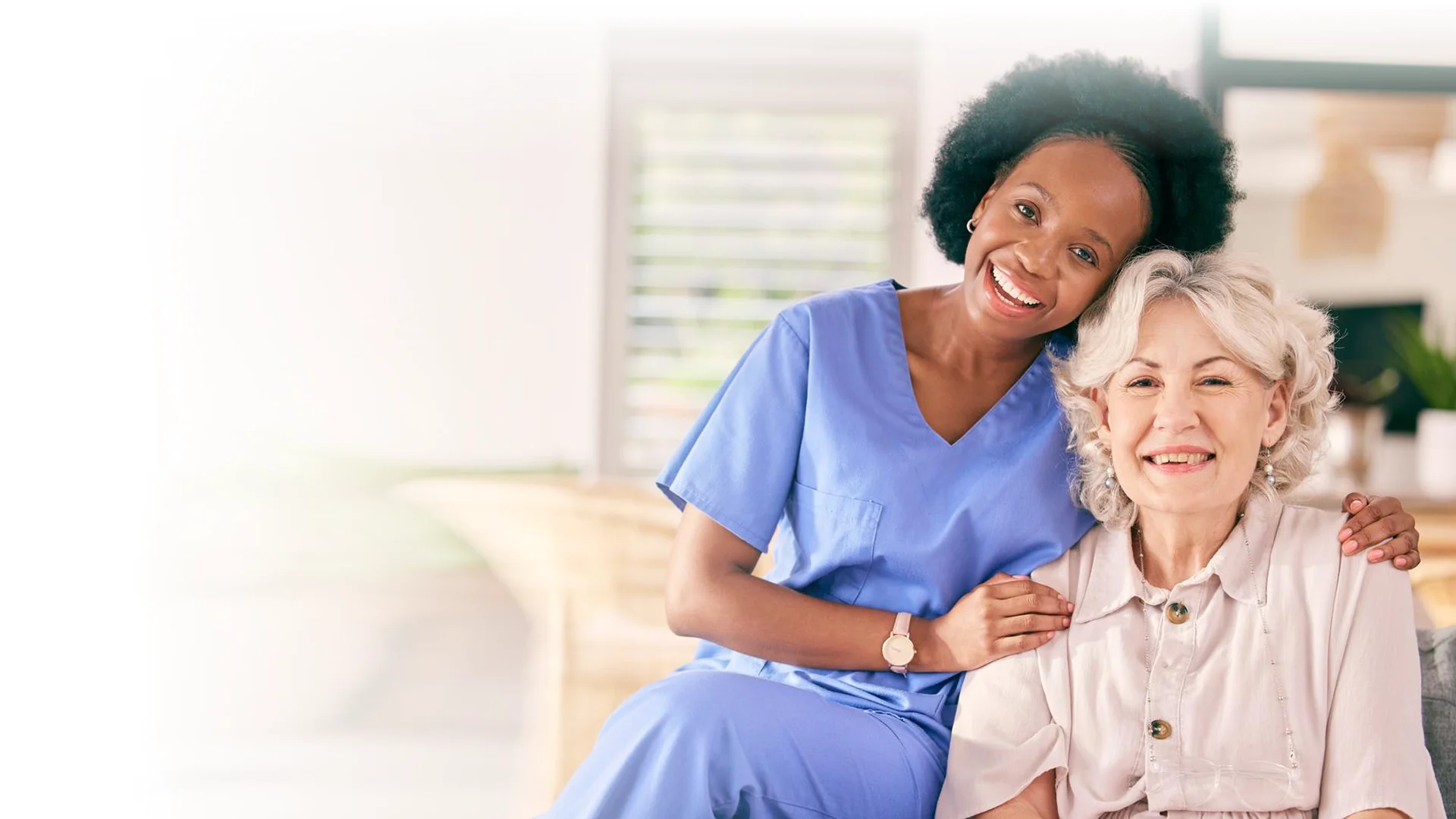 Happy caregiver with smiling senior woman at home