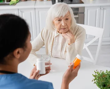 Senior woman discussing medication with caregiver