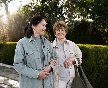 Caregiver walking with elderly woman outdoors