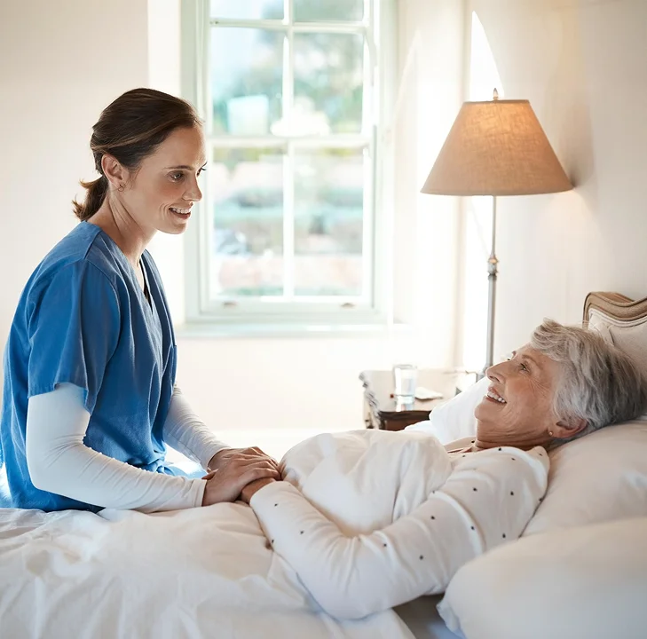 Caregiver providing bedside support to a senior woman