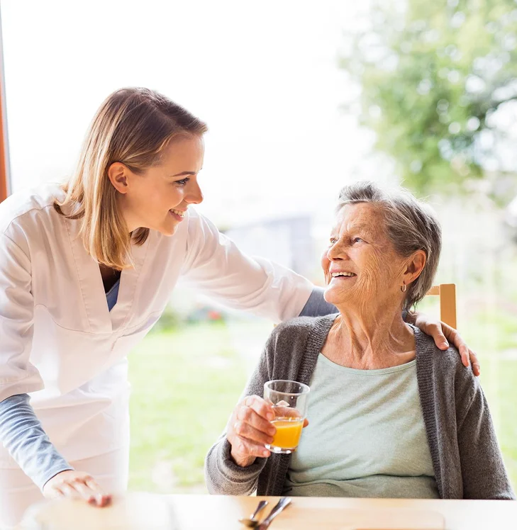 Caregiver talking with an elderly woman during mealtime