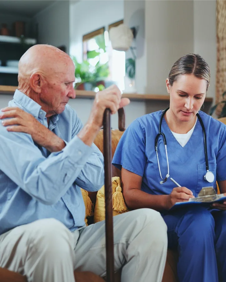 Caregiver talking with a senior man during a home visit