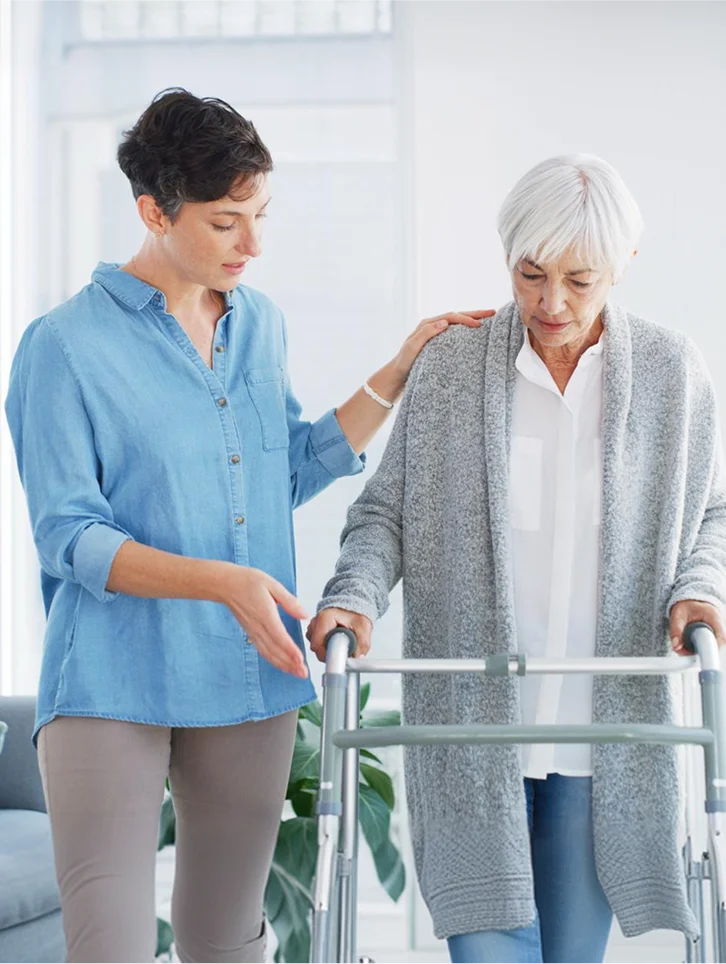 Caregiver assisting a senior woman with walker mobility