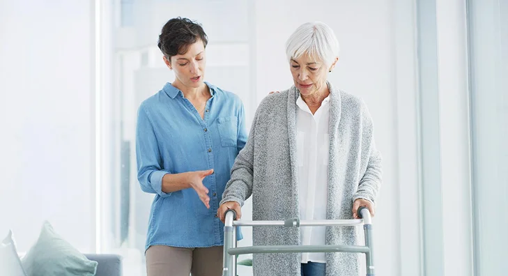 Caregiver assisting an elderly woman with a walker