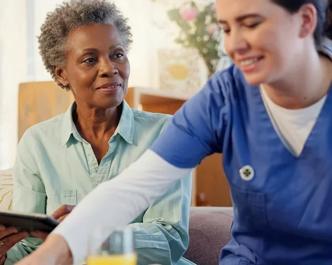 Caregiver assisting a senior woman with a tablet