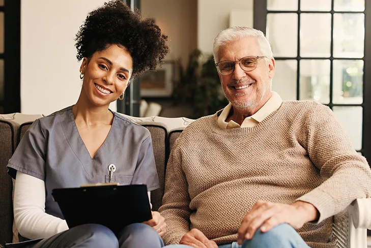 Caregiver sitting with an elderly man during a home visit