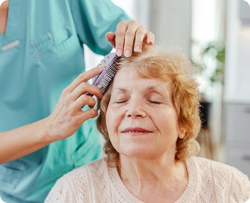 Caregiver gently combing the hair of a smiling senior woman