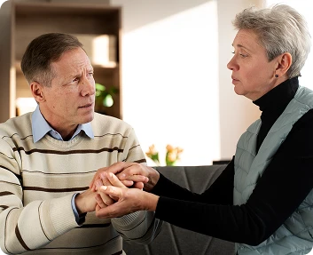 Senior man and woman holding hands during a comforting conversation indoors