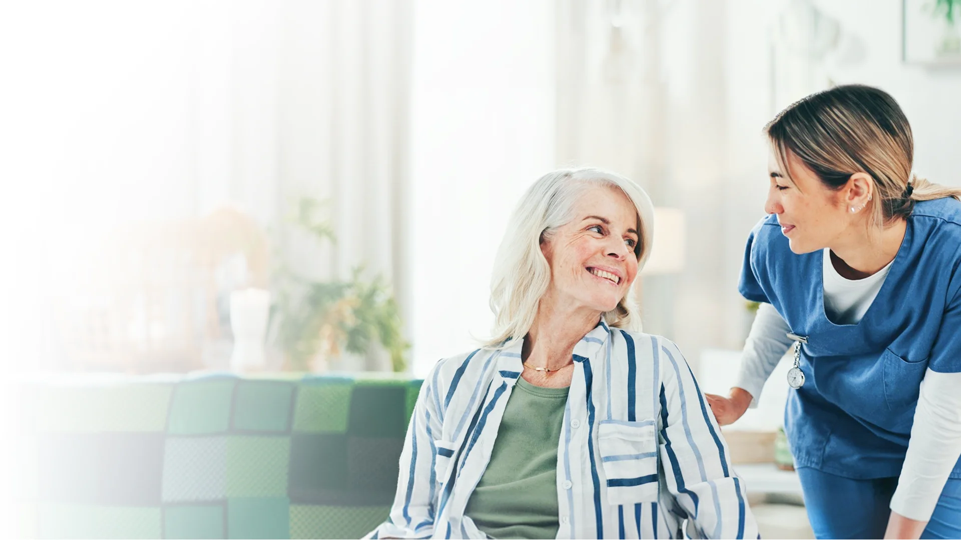 Caregiver speaking with a smiling elderly woman at home