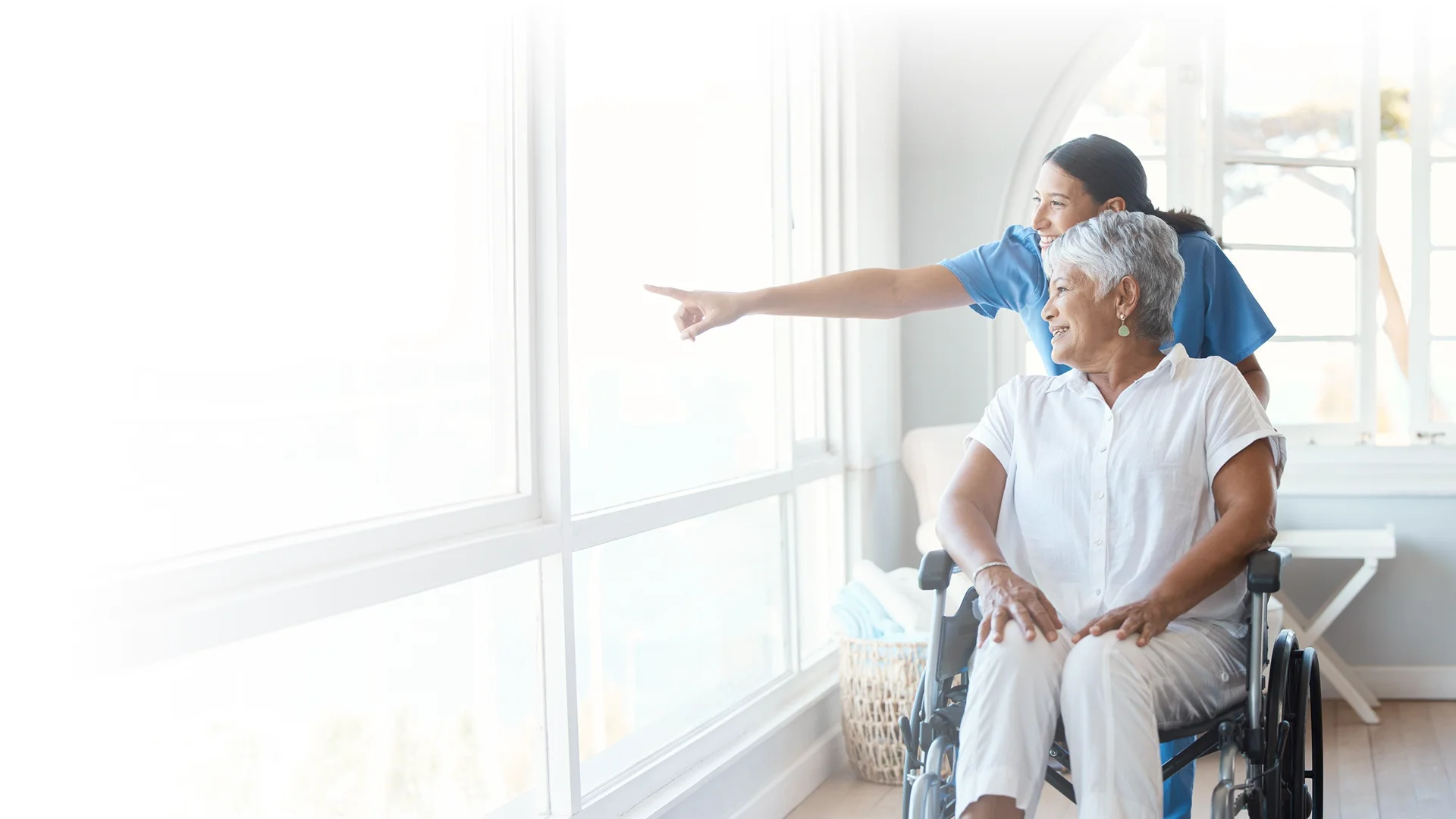 Caregiver helping an elderly man stand from a wheelchair