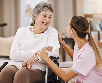Caregiver comforting an elderly woman in a wheelchair