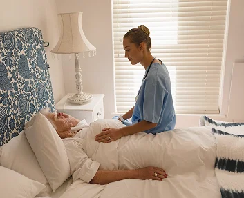 caregiver tending to elderly patient lying in bed