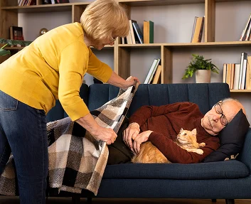 Caregiver covering a resting senior with a blanket