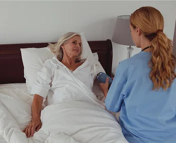 Nurse checking a senior patient's blood pressure at bedside