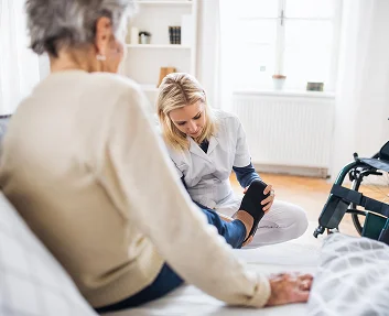 Physical therapist assisting a senior woman with leg rehabilitation