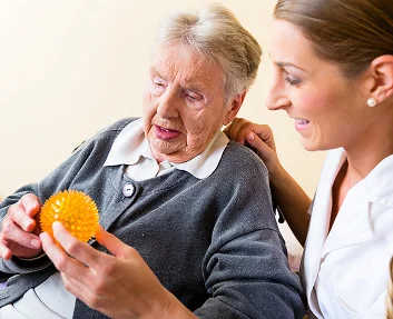 Caregiver helping a senior woman with hand therapy