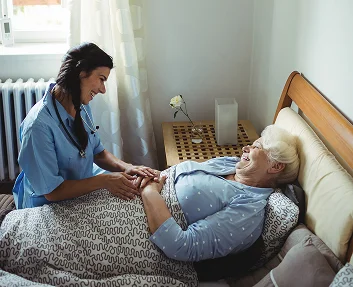 Caregiver comforting a senior woman in bed