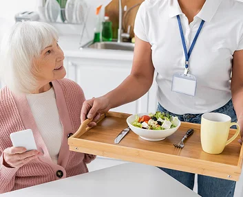 Caregiver serving a healthy meal to a senior woman
