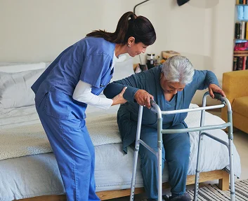 Caregiver helping elderly patient stand with a walker