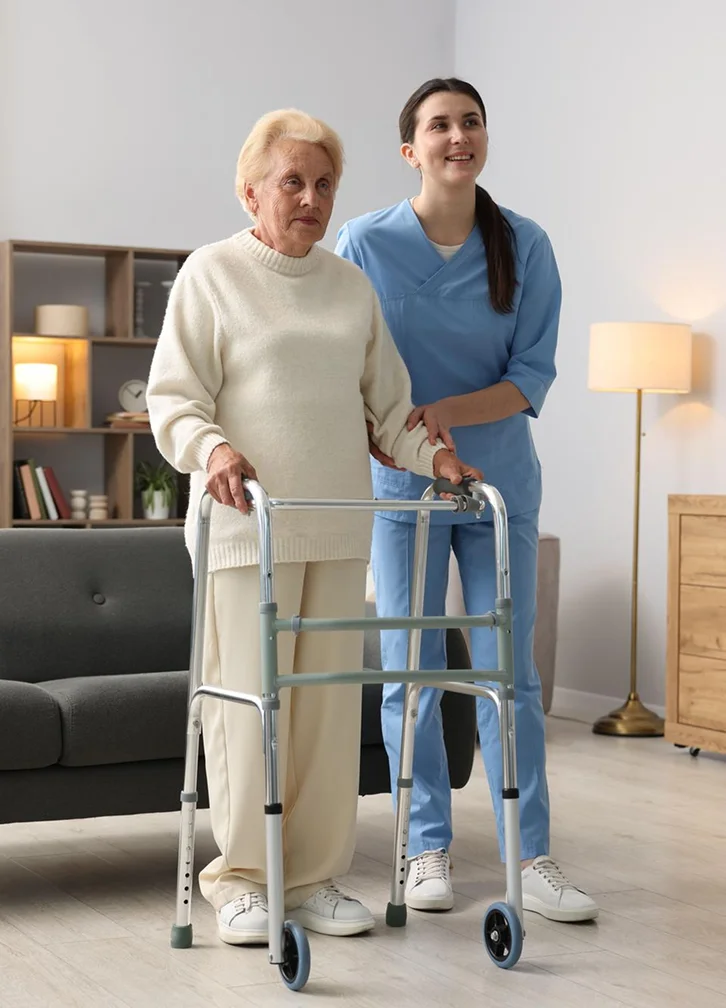 Caregiver assisting a senior woman walking with a walker