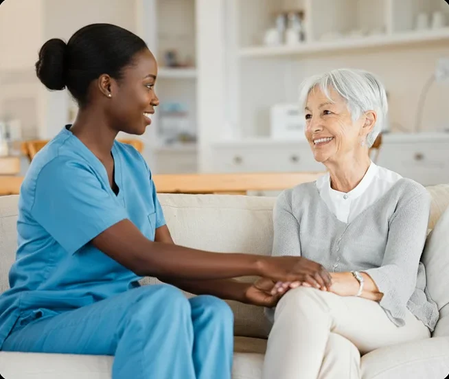 Caregiver holding hands with a senior woman on a sofa
