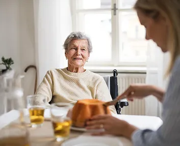 Caregiver preparing a meal for a senior woman at home