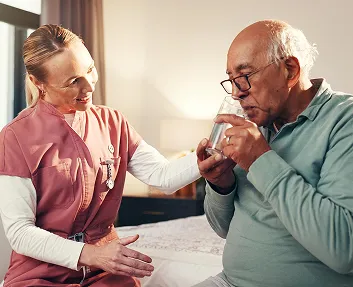 Caregiver assisting a senior man with medication