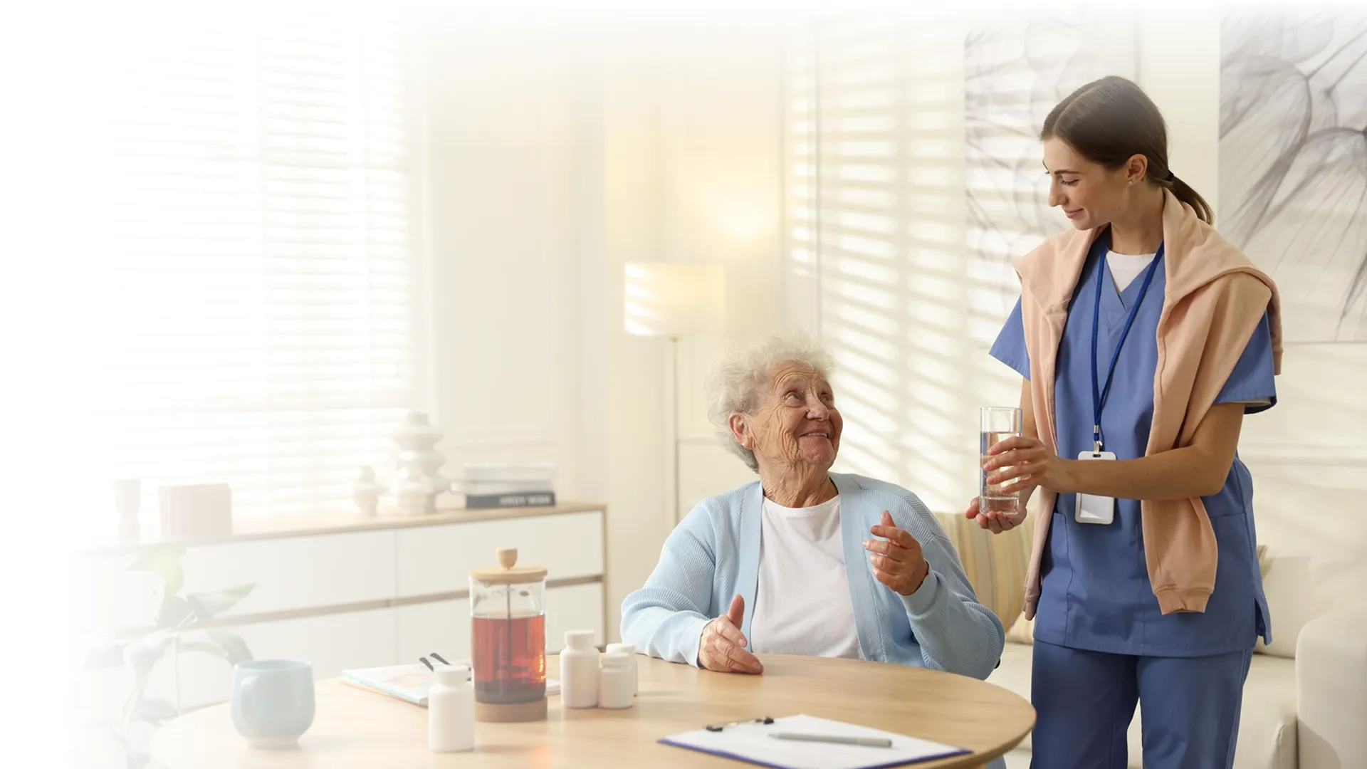 Caregiver offering a glass of water to a senior woman at home